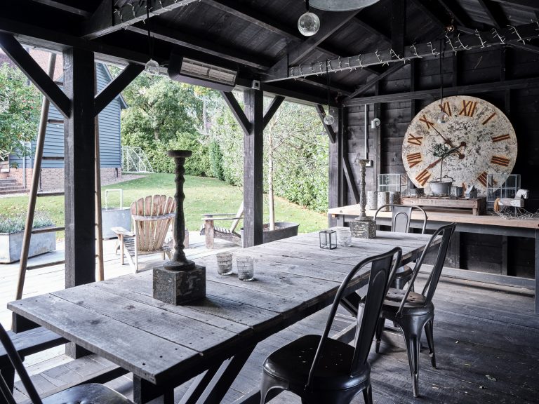 OUT DOOR DINING AREA WITH HUGE ANTIQUE CLOCK FACE AND RUSTIC DINING ATBLE AND CHAIRS - HAGUE BARN HENLEY ON THAMES, RG9 - SHOOTFACTORY - OTHER UK LOCATION HOUSE