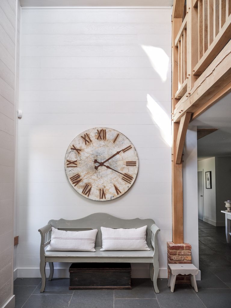 DOUBLE HEIGHT ENTRANCE HALL WITH OAK BEAMS - RUSTIC WOODEN BENCH AND A HUGE WALL MOUNTED CLOCK FACE - HAGUE BARN HENLEY ON THAMES, RG9 - SHOOTFACTORY - OTHER UK LOCATION HOUSE