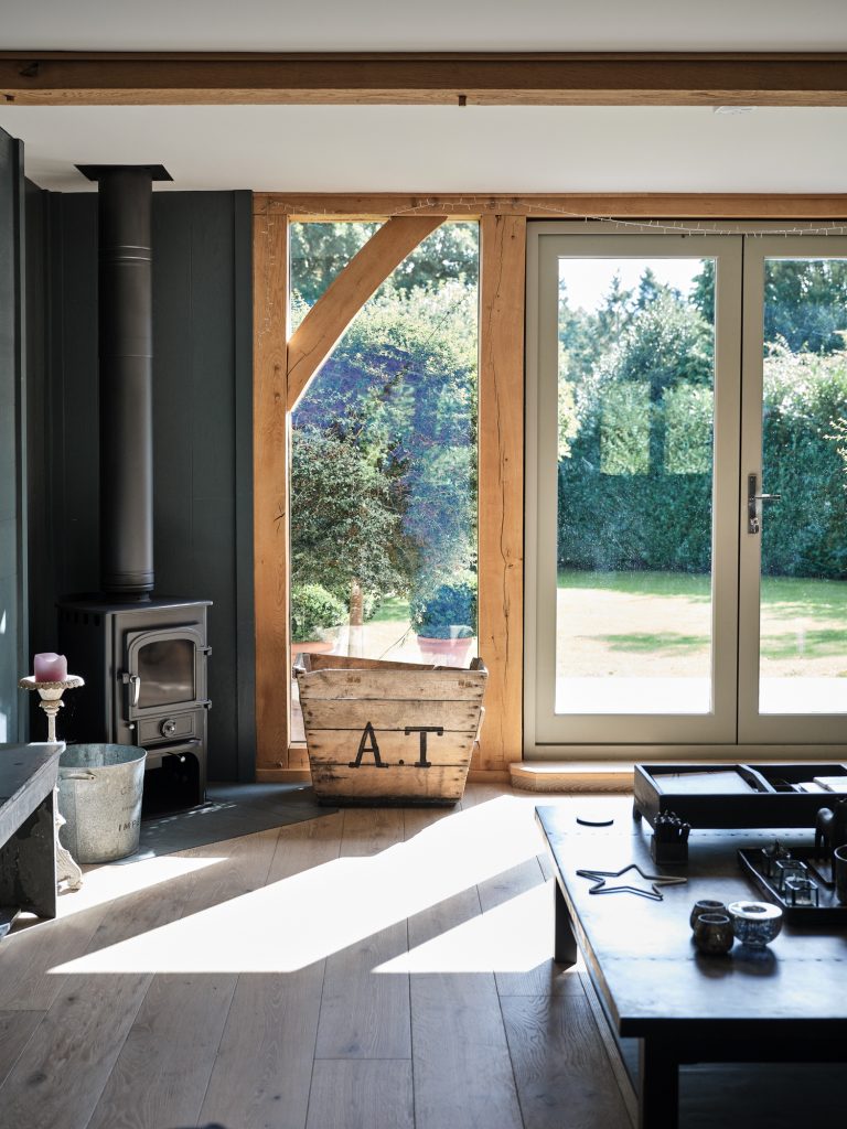 WOOD BURNING STOVE WITH WODDEN FRAMED GLASS DOORS AND VIEW OVER GARDEN - HAGUE BARN HENLEY ON THAMES, RG9 - SHOOTFACTORY - OTHER UK LOCATION HOUSE