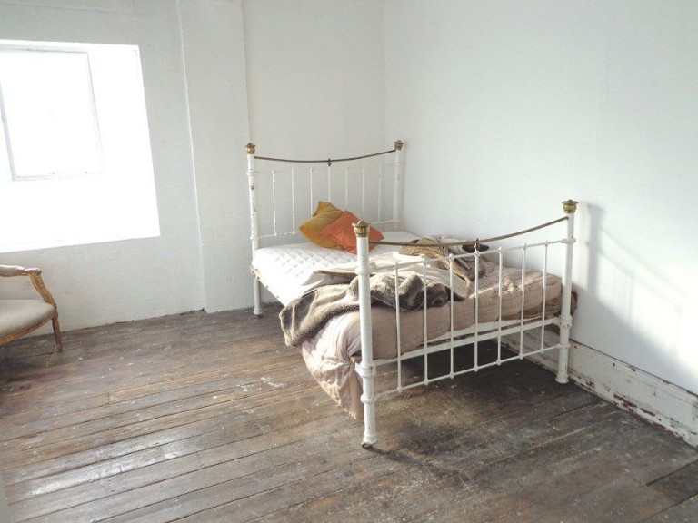 Metal framed bed with orange cushion / Blackheath, London, Se13 / Shootfactory Location